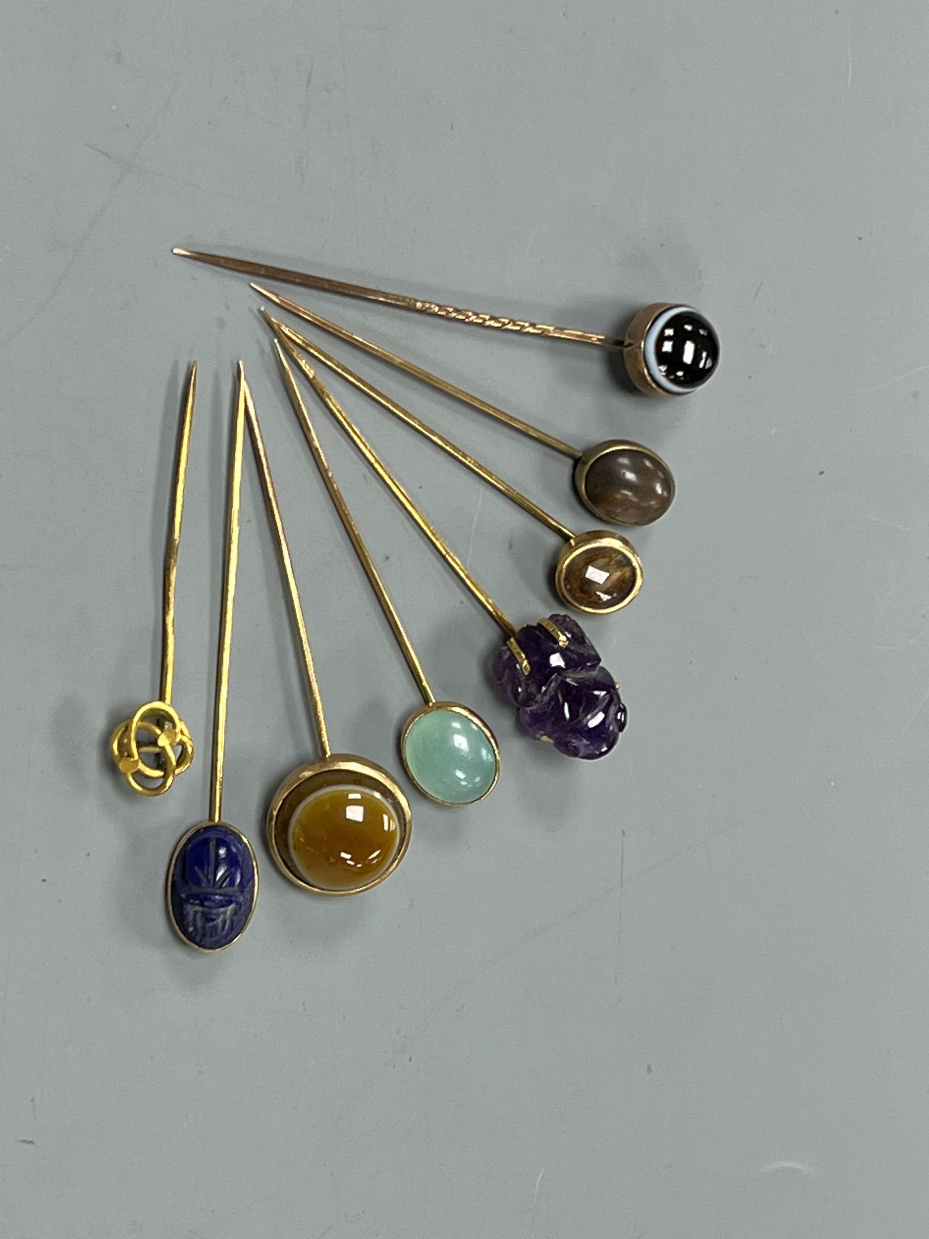 A small collection of eight assorted mainly yellow metal and chalcedony set stick pins, including Scarab, amethyst frog and banded agate